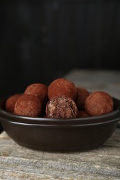 Photo of Delicious chocolate candies powdered with cocoa on wooden table