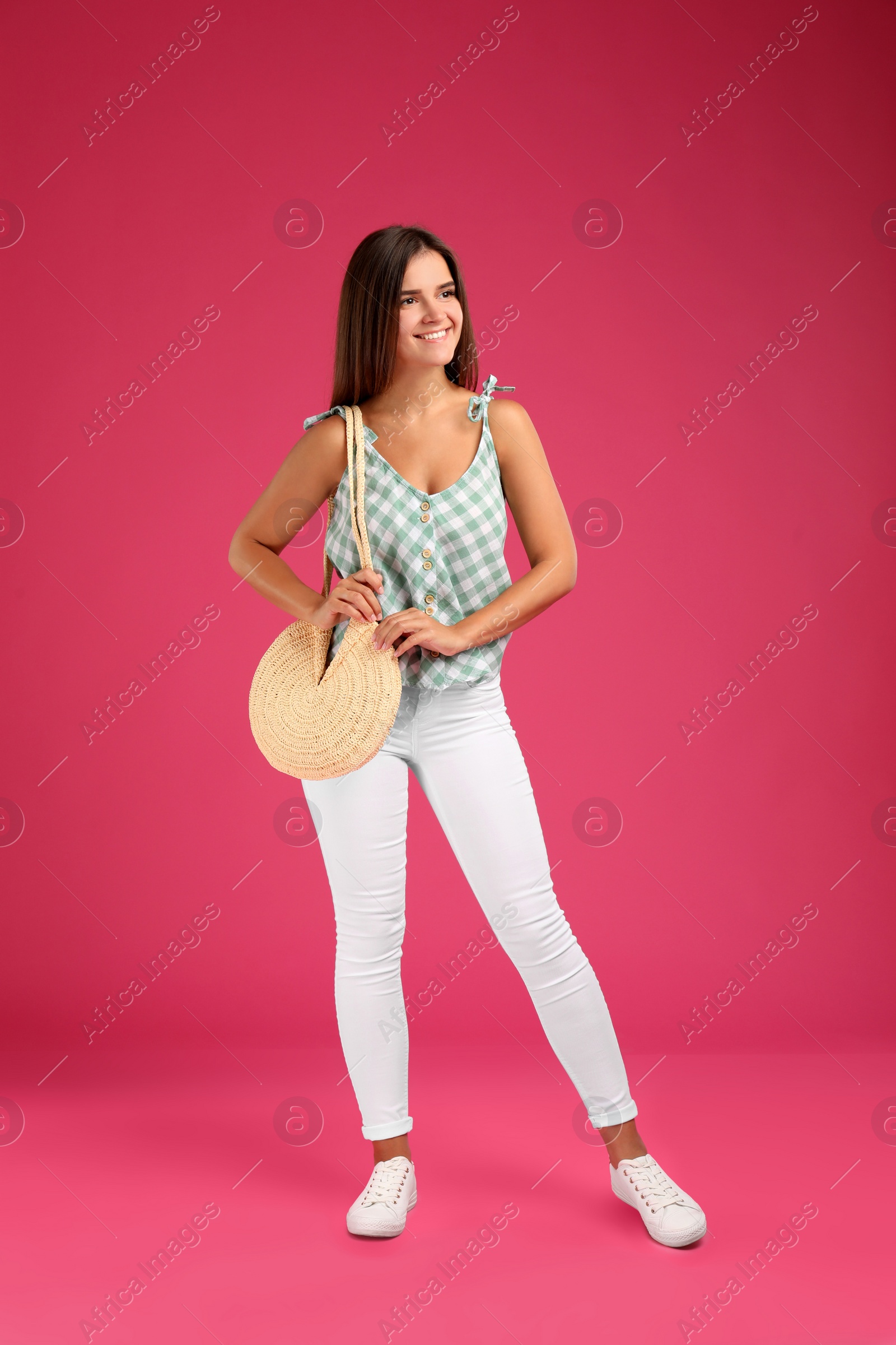 Photo of Young woman with stylish straw bag on pink background