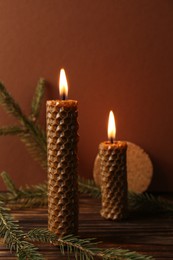 Photo of Stylish elegant beeswax candles with spruce branches on wooden table