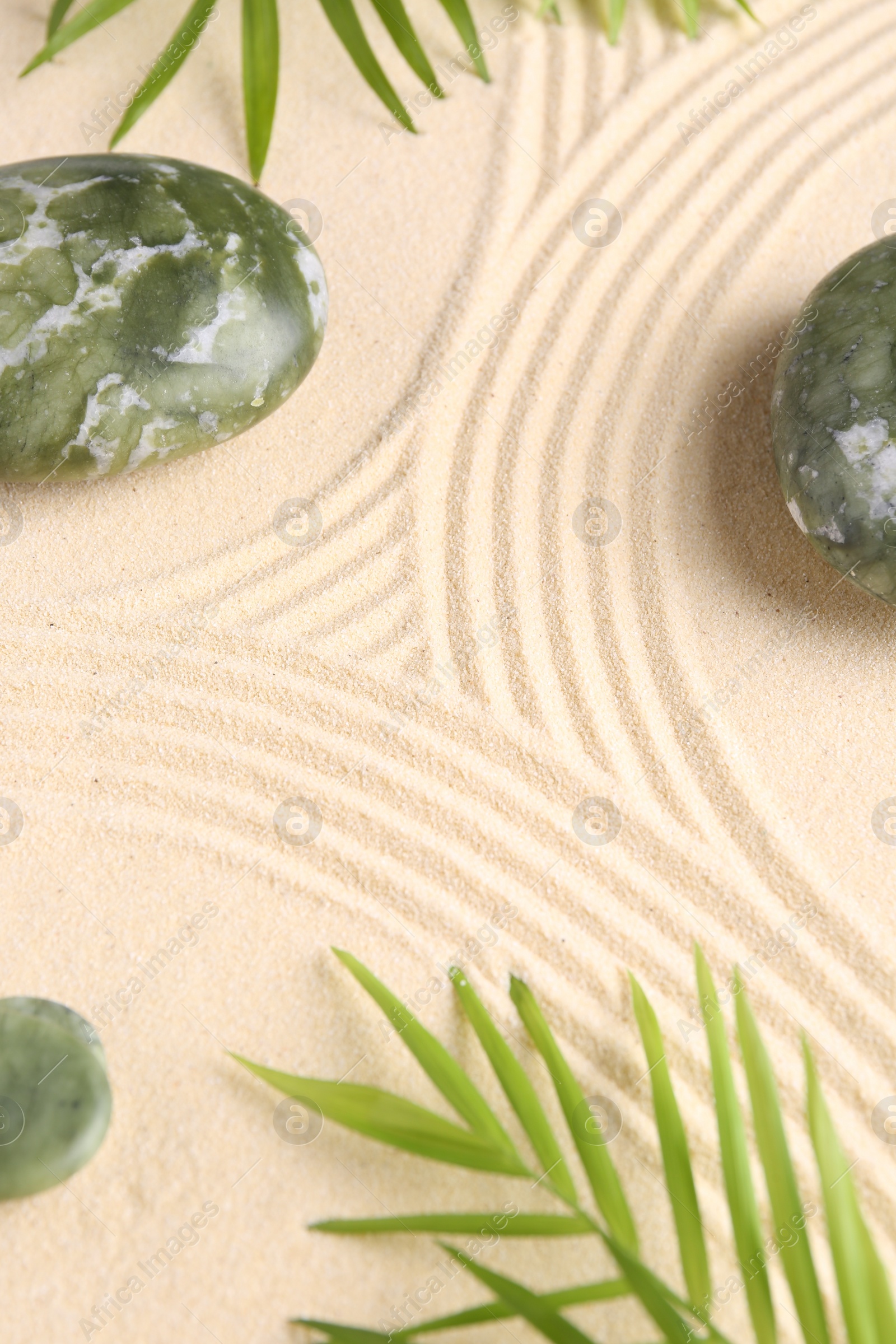 Photo of Zen concept. Stones, leaves and pattern on beige sand, closeup. Space for text