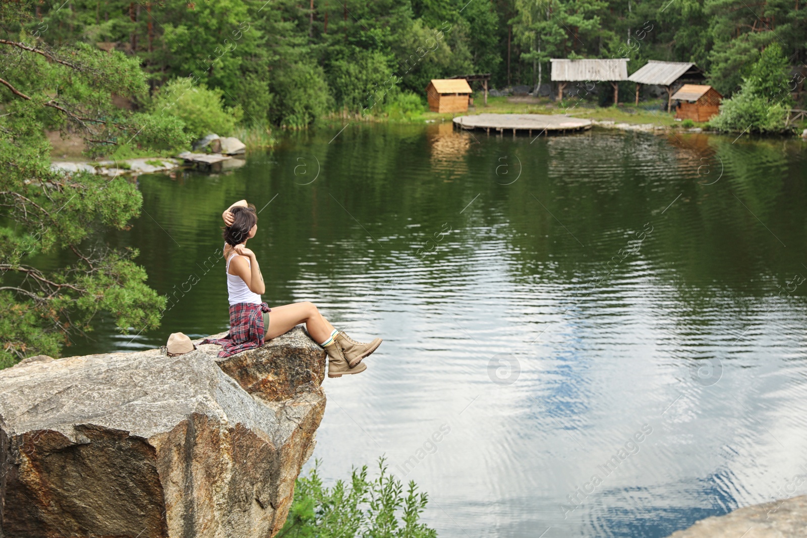 Photo of Young woman on rocky mountain near lake. Camping season