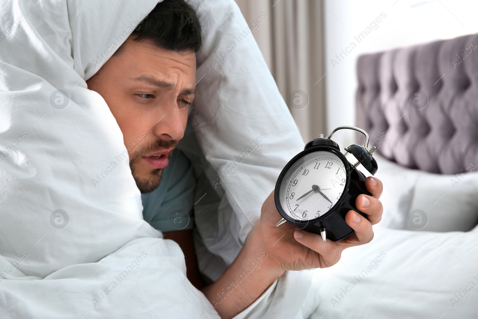 Photo of Sleepy man with alarm clock at home in morning