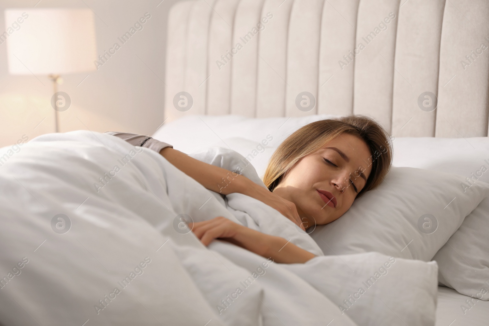 Photo of Woman under warm white blanket sleeping in bed indoors