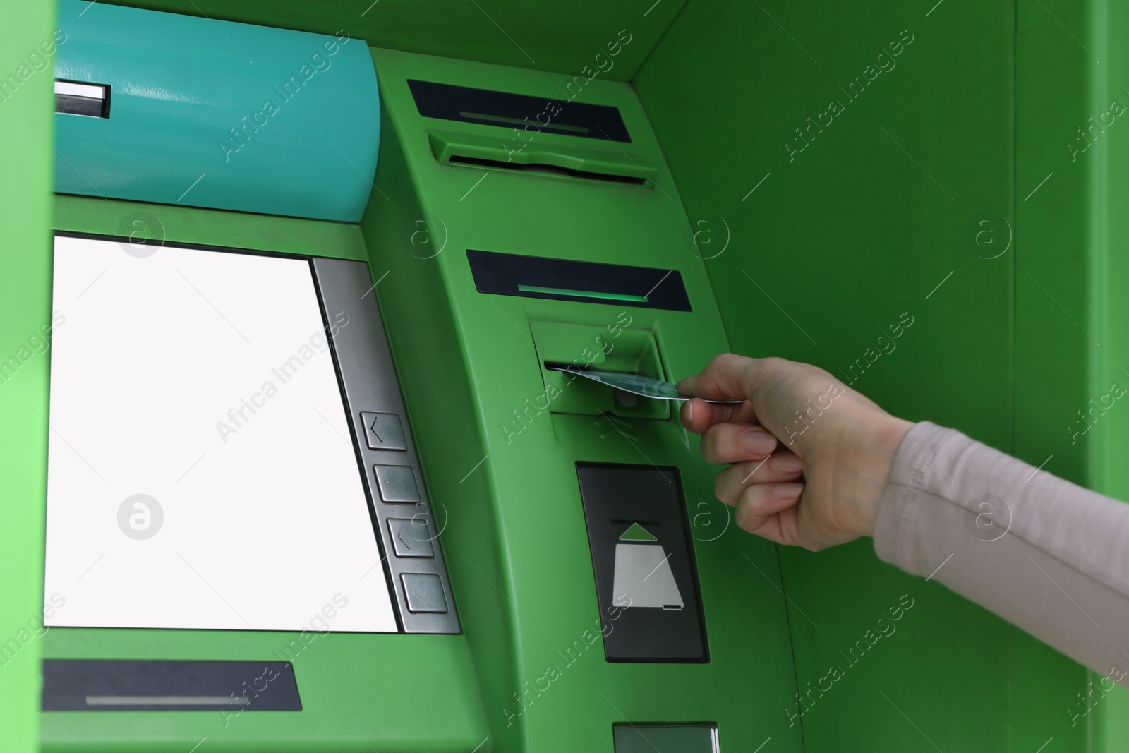 Photo of Woman inserting credit card into green cash machine, closeup