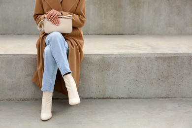 Photo of Stylish woman with trendy beige bag on stairs outdoors, closeup