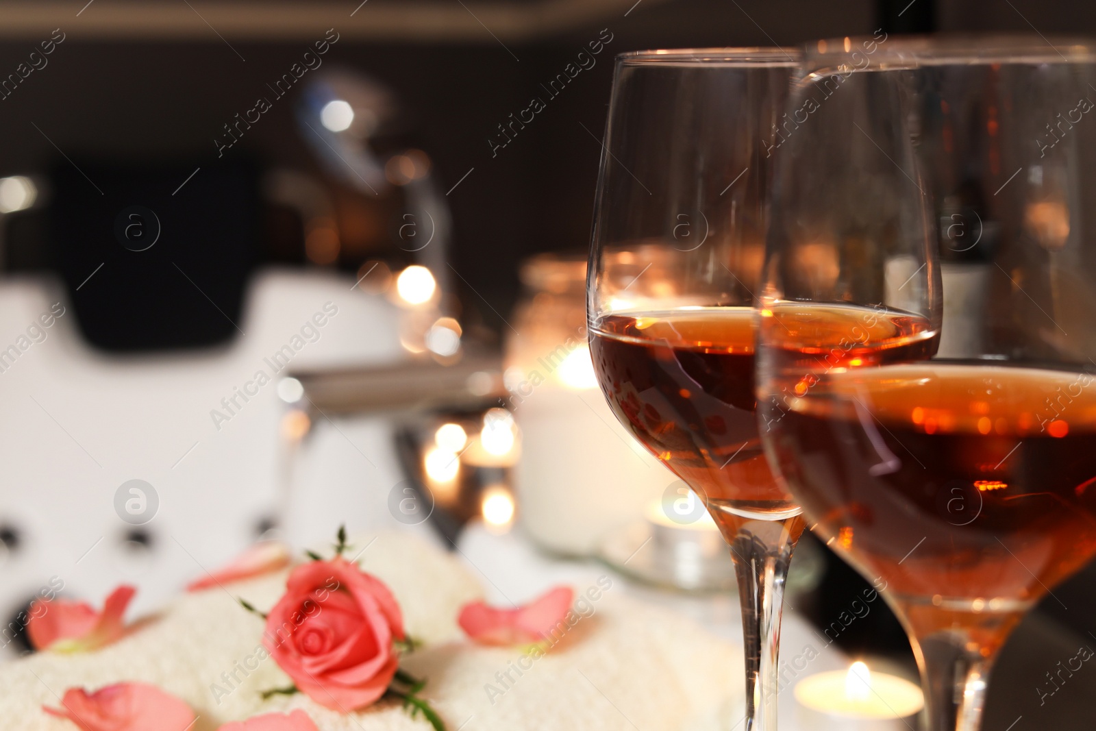 Photo of Glasses of wine on tub in bathroom, closeup with space for text. Romantic atmosphere