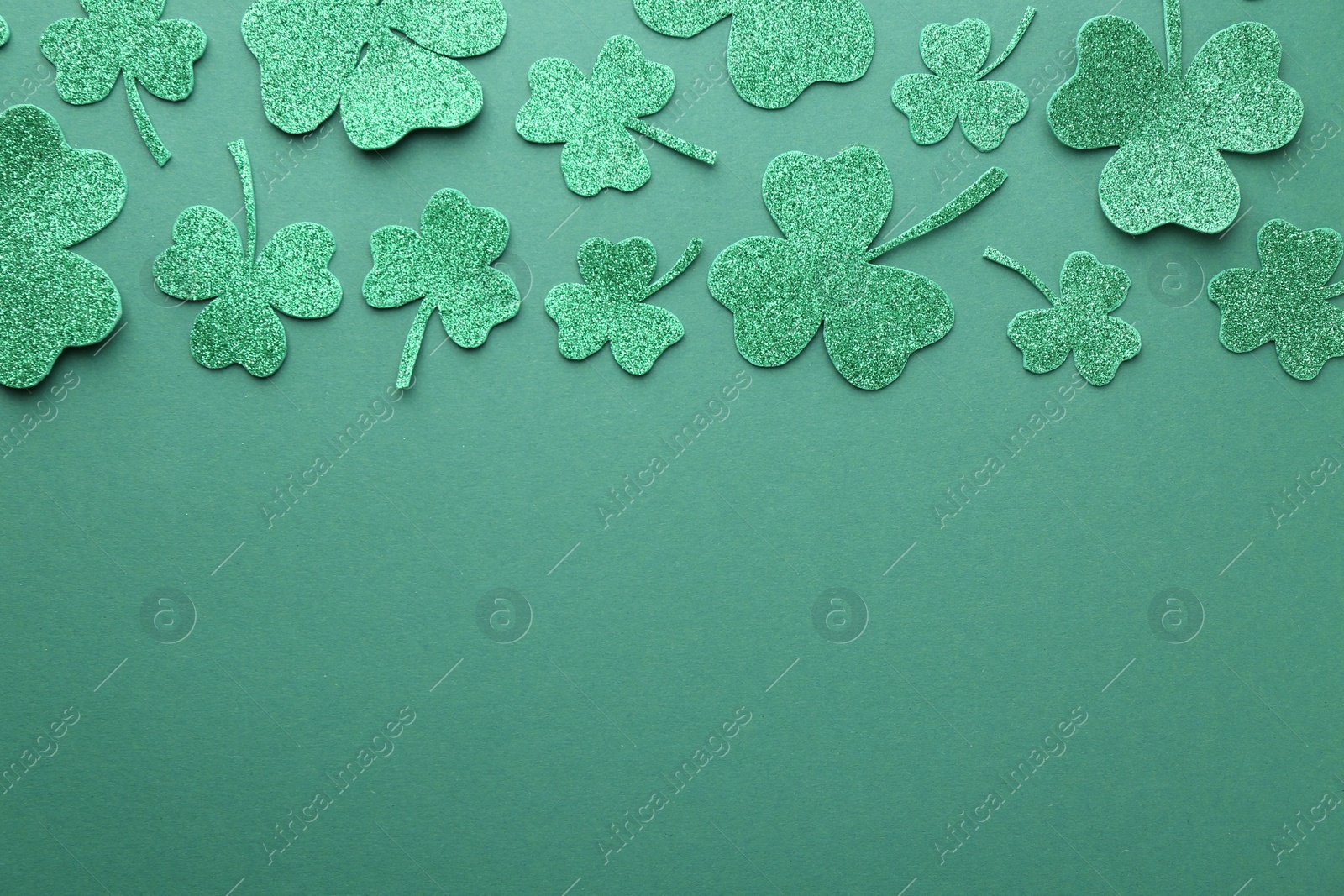 Photo of St. Patrick's day. Decorative clover leaves on green background, flat lay. Space for text