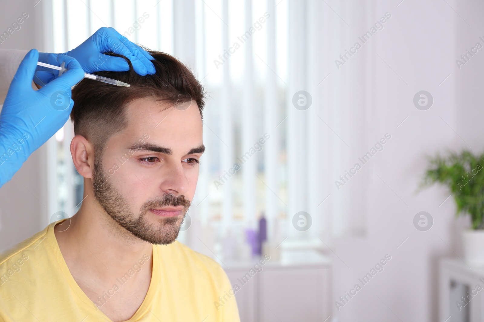 Photo of Young man with hair loss problem receiving injection in salon