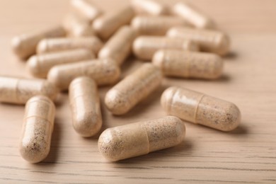 Photo of Gelatin capsules on wooden table, closeup view