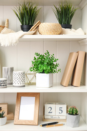 Photo of White shelving unit with plants and different decorative stuff