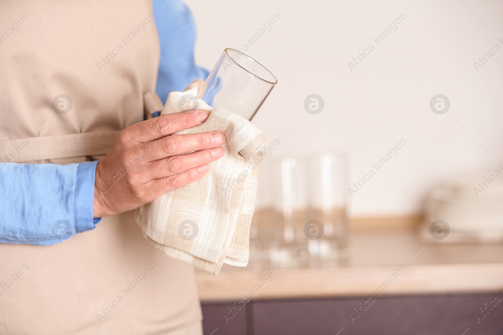 Photo of Woman wiping glass with towel in kitchen, closeup. Space for text