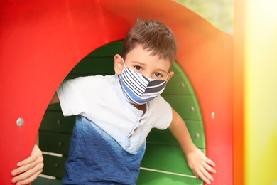 Little boy with medical face mask on playground during covid-19 quarantine