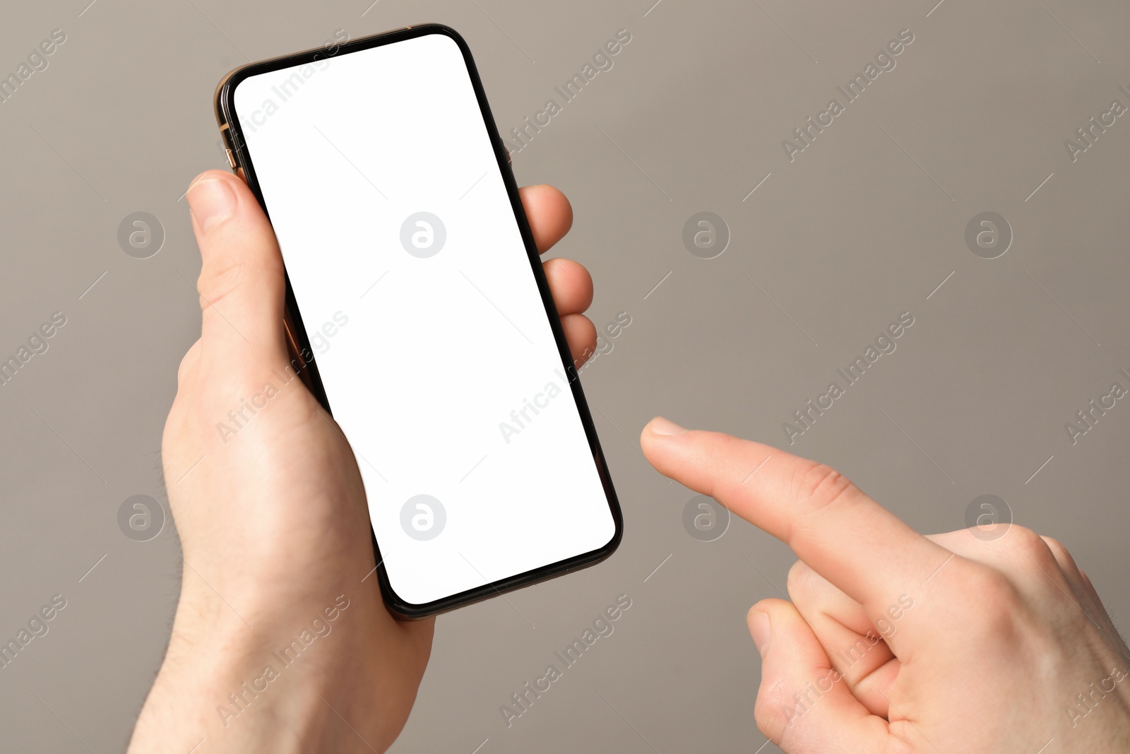 Photo of Man holding smartphone with blank screen on light grey background, closeup. Mockup for design