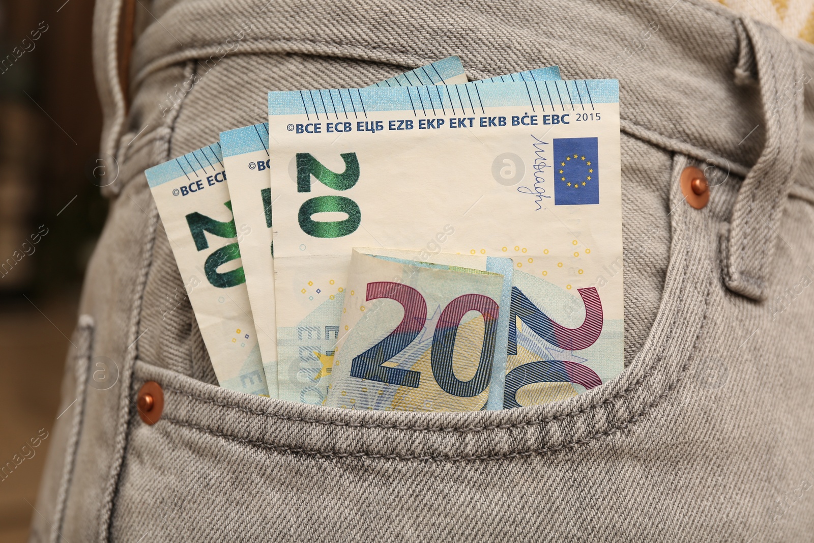 Photo of Euro banknotes in pocket of grey jeans, closeup. Spending money