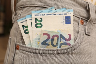 Photo of Euro banknotes in pocket of grey jeans, closeup. Spending money