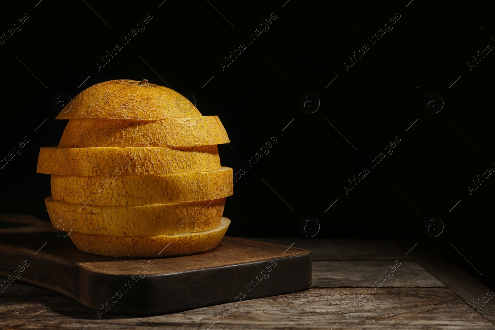 Photo of Sliced ripe melon on table against black background. Space for text