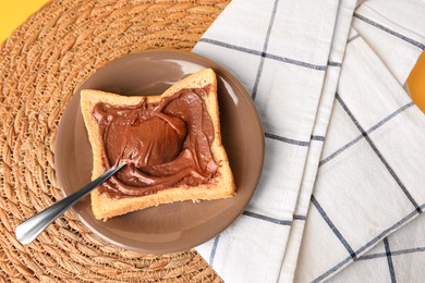 Photo of Tasty toast with chocolate paste on wicker mat, above view