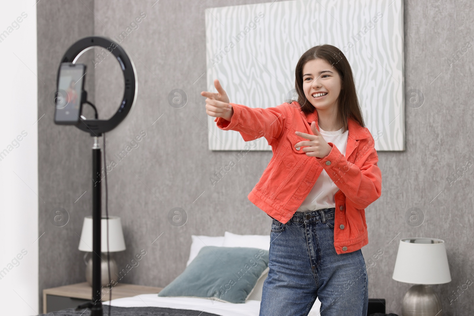 Photo of Smiling teenage blogger dancing while streaming at home