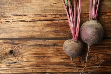 Photo of Raw ripe beets on wooden table, flat lay. Space for text