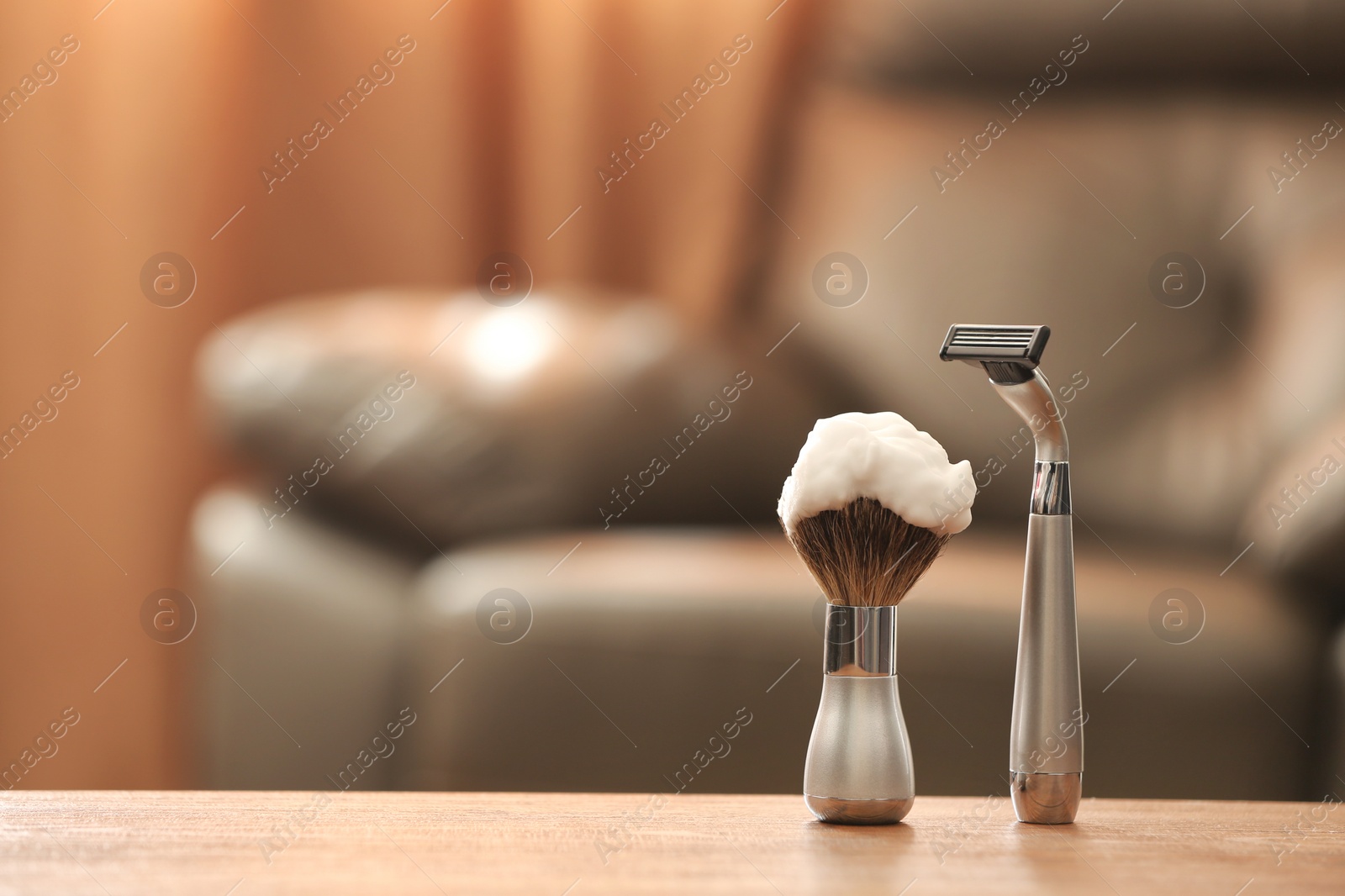 Photo of Shaving brush and razor on table against blurred background with space for text