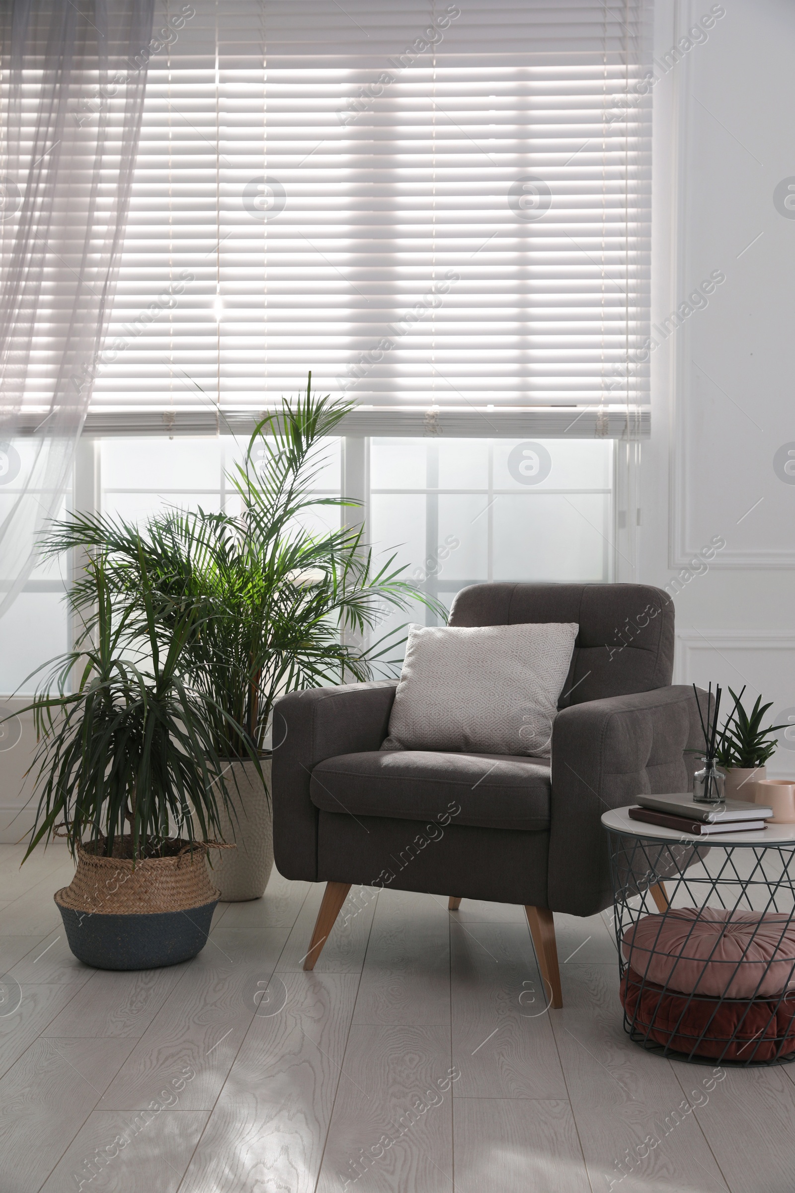 Photo of Comfortable place for rest with grey armchair near window indoors