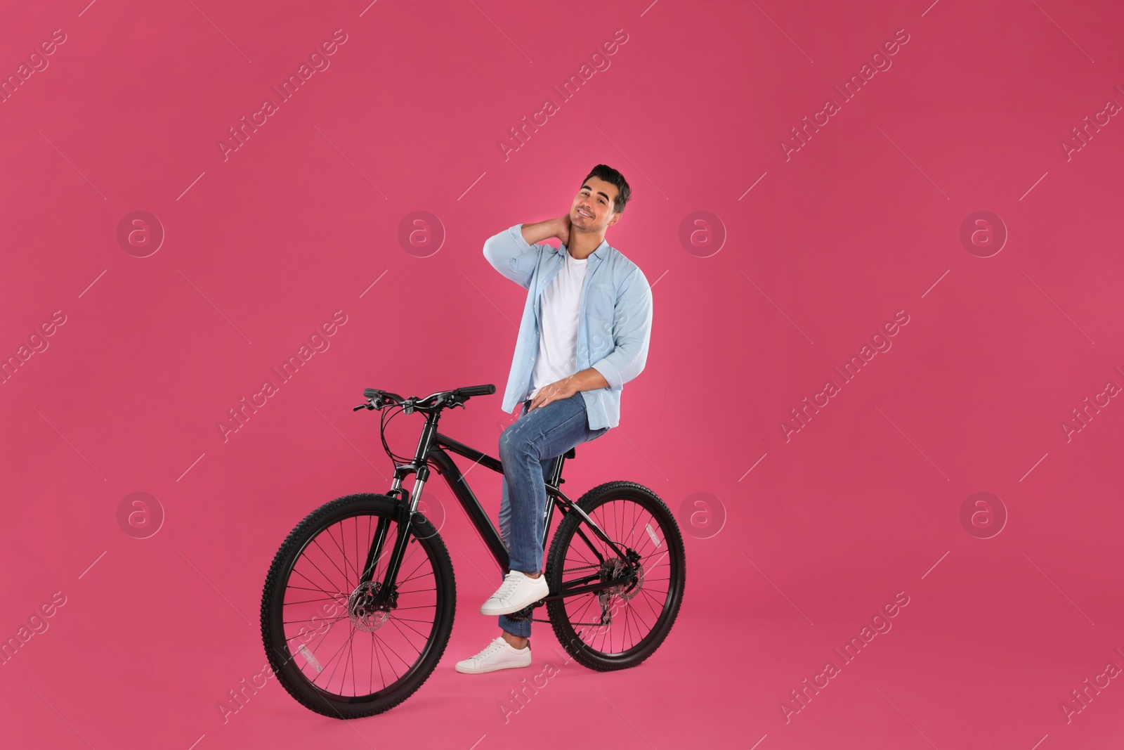 Photo of Handsome young man with modern bicycle on pink background