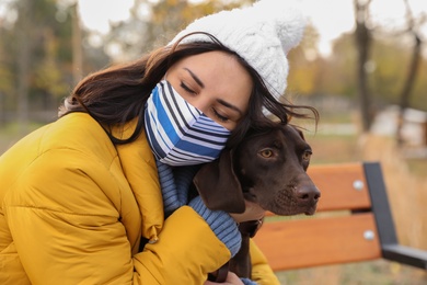 Woman in protective mask with German Shorthaired Pointer outdoors. Walking dog during COVID-19 pandemic