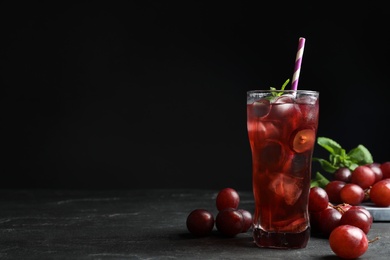 Photo of Delicious grape soda water on black table, space for text. Refreshing drink