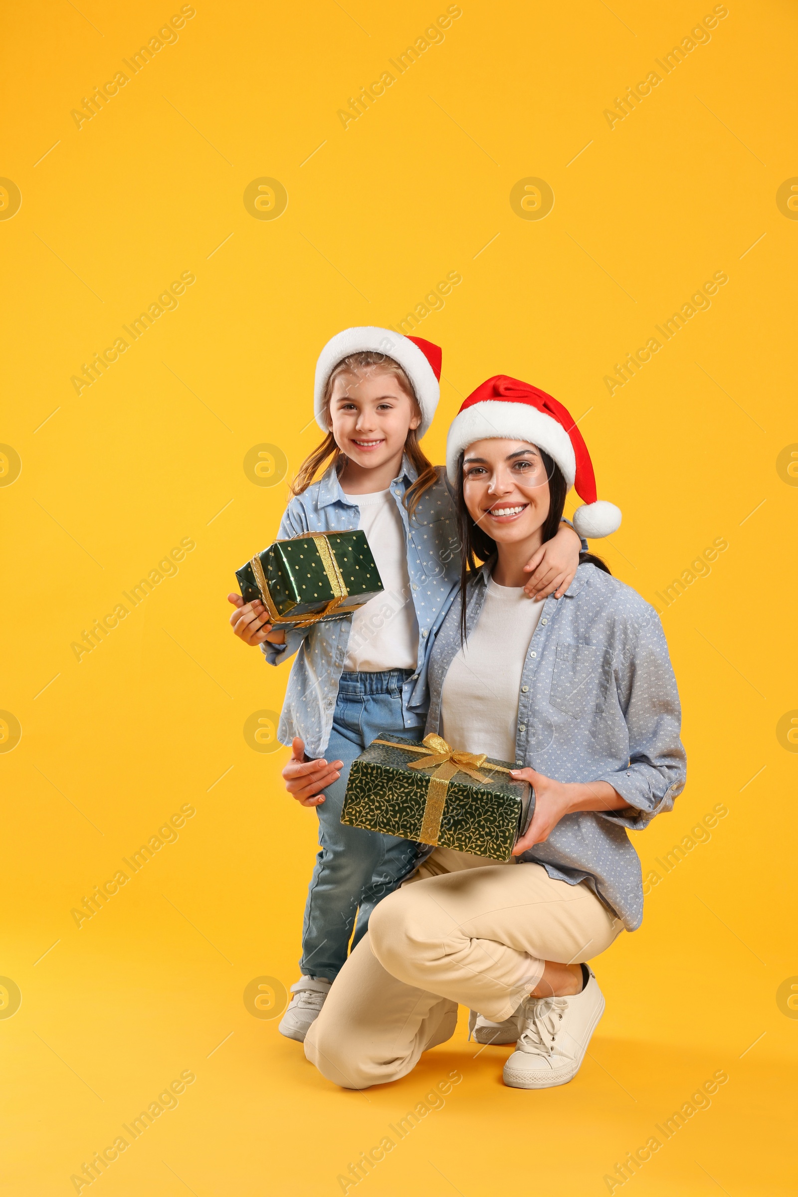 Photo of Mother and daughter with Christmas gifts on yellow background