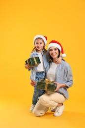 Photo of Mother and daughter with Christmas gifts on yellow background