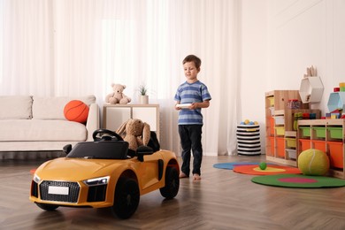 Little child playing with remote control car in room