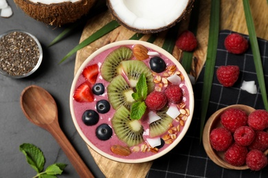 Photo of Delicious acai smoothie with granola and fruits served on black table, flat lay