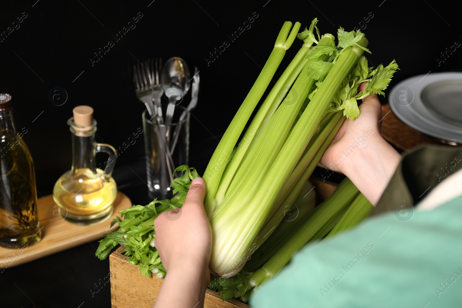 Photo of Woman with fresh green celery in kitchen, closeup