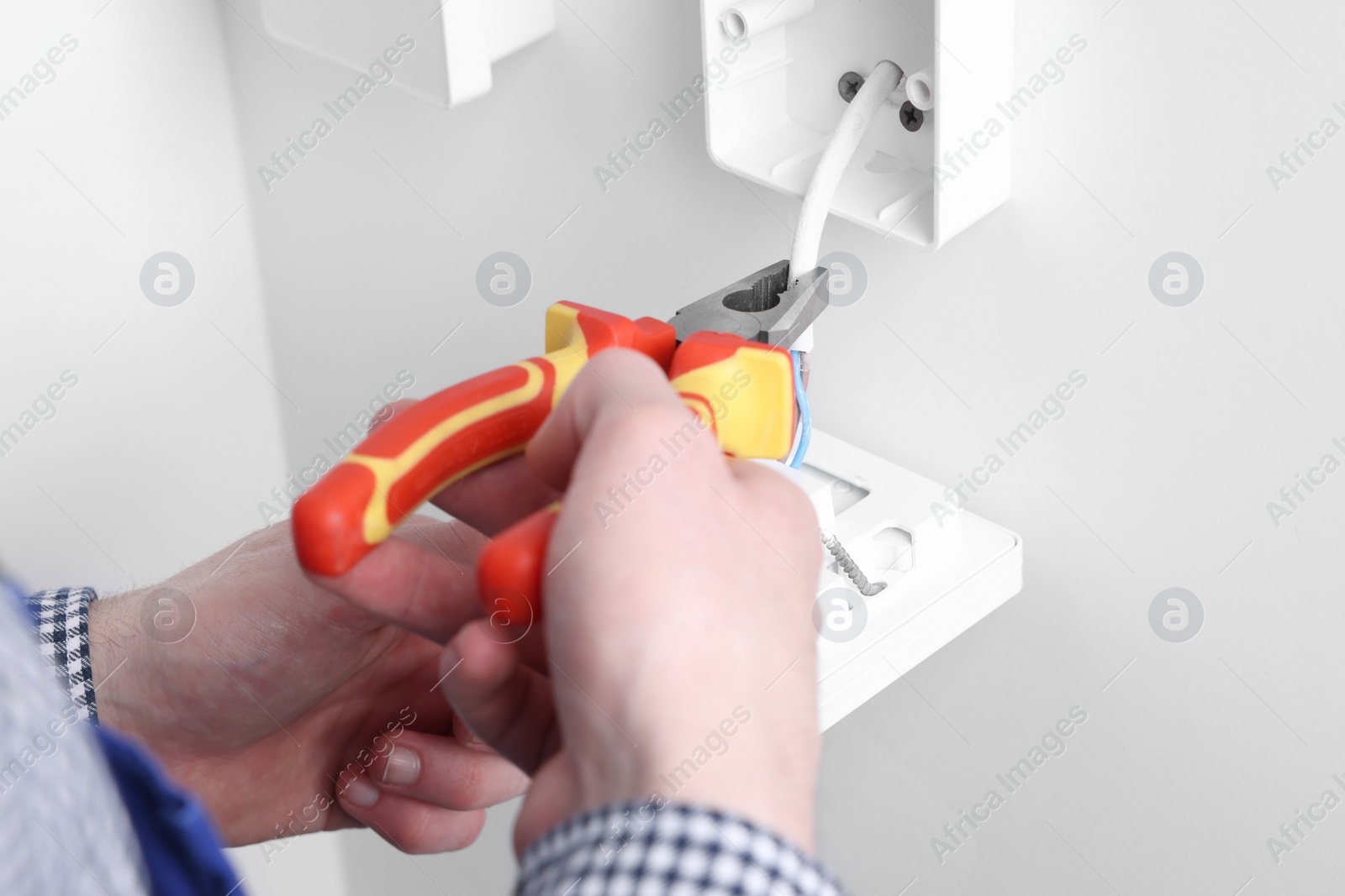 Photo of Professional repairman fixing electric house appliance with pliers indoors, closeup