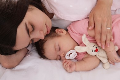 Photo of Young mother resting near her sleeping baby on bed, closeup
