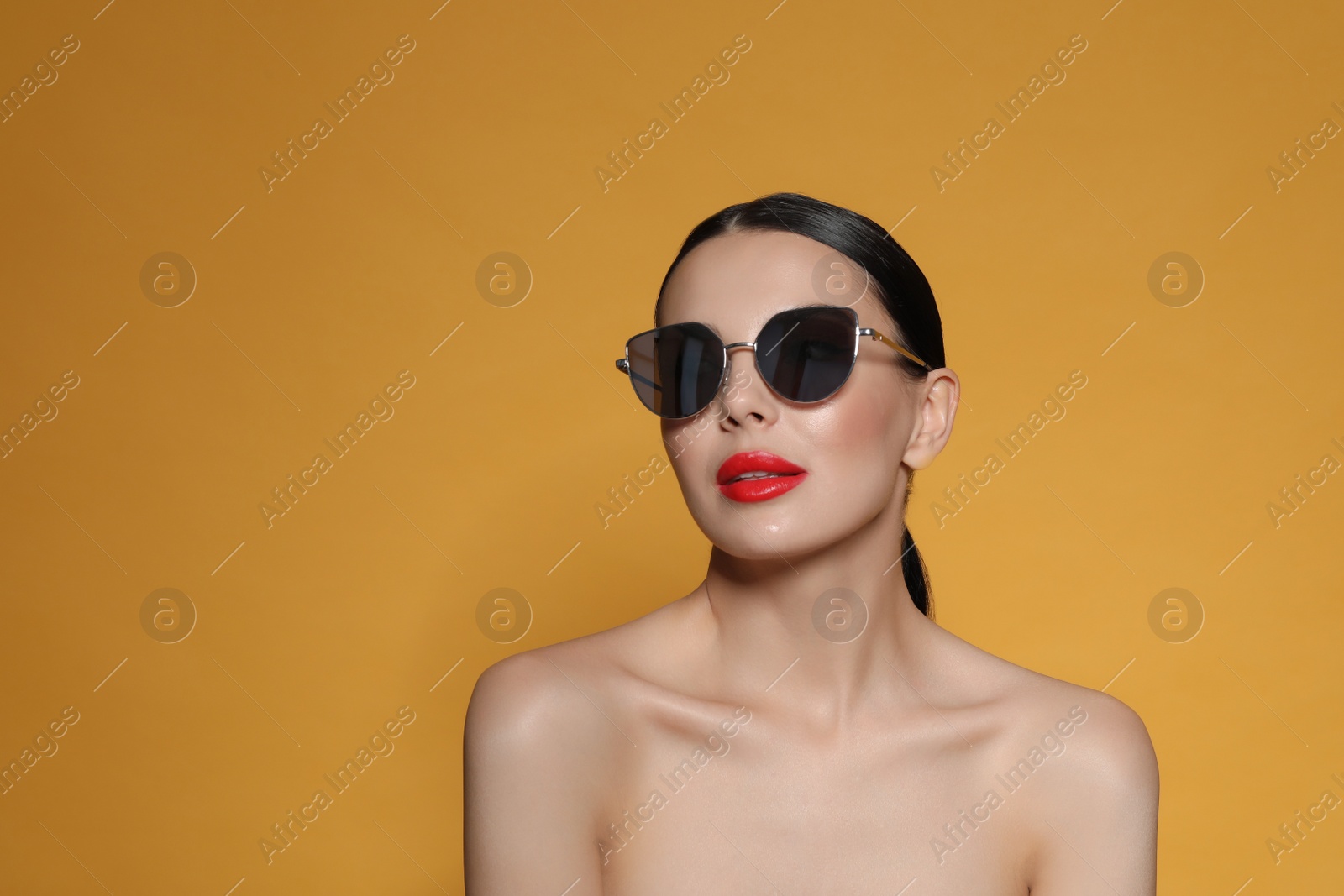 Photo of Attractive woman in fashionable sunglasses against orange background. Space for text