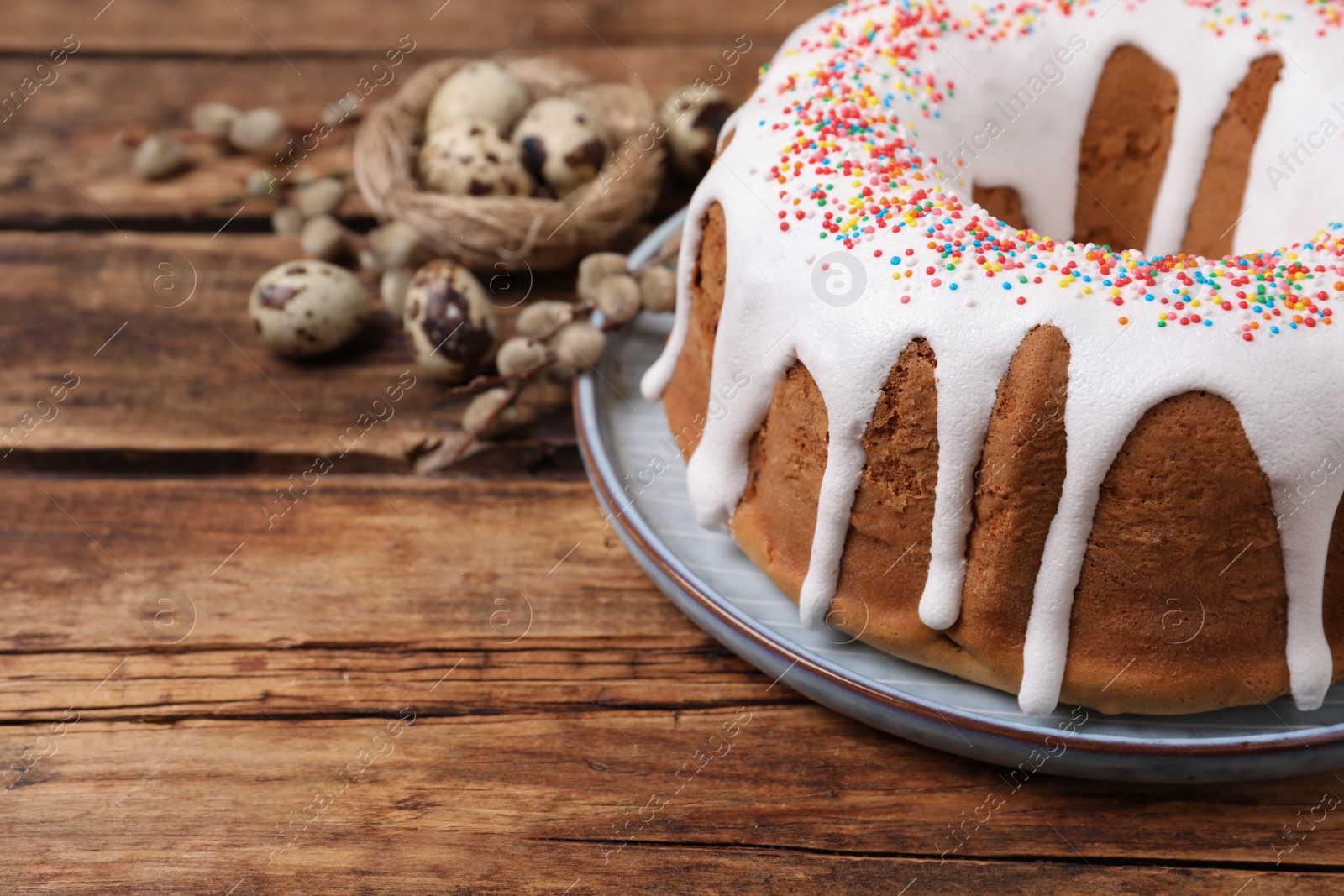 Photo of Glazed Easter cake with sprinkles on wooden table, closeup. Space for text