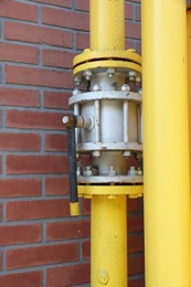 Photo of Yellow gas pipe near red brick wall outdoors