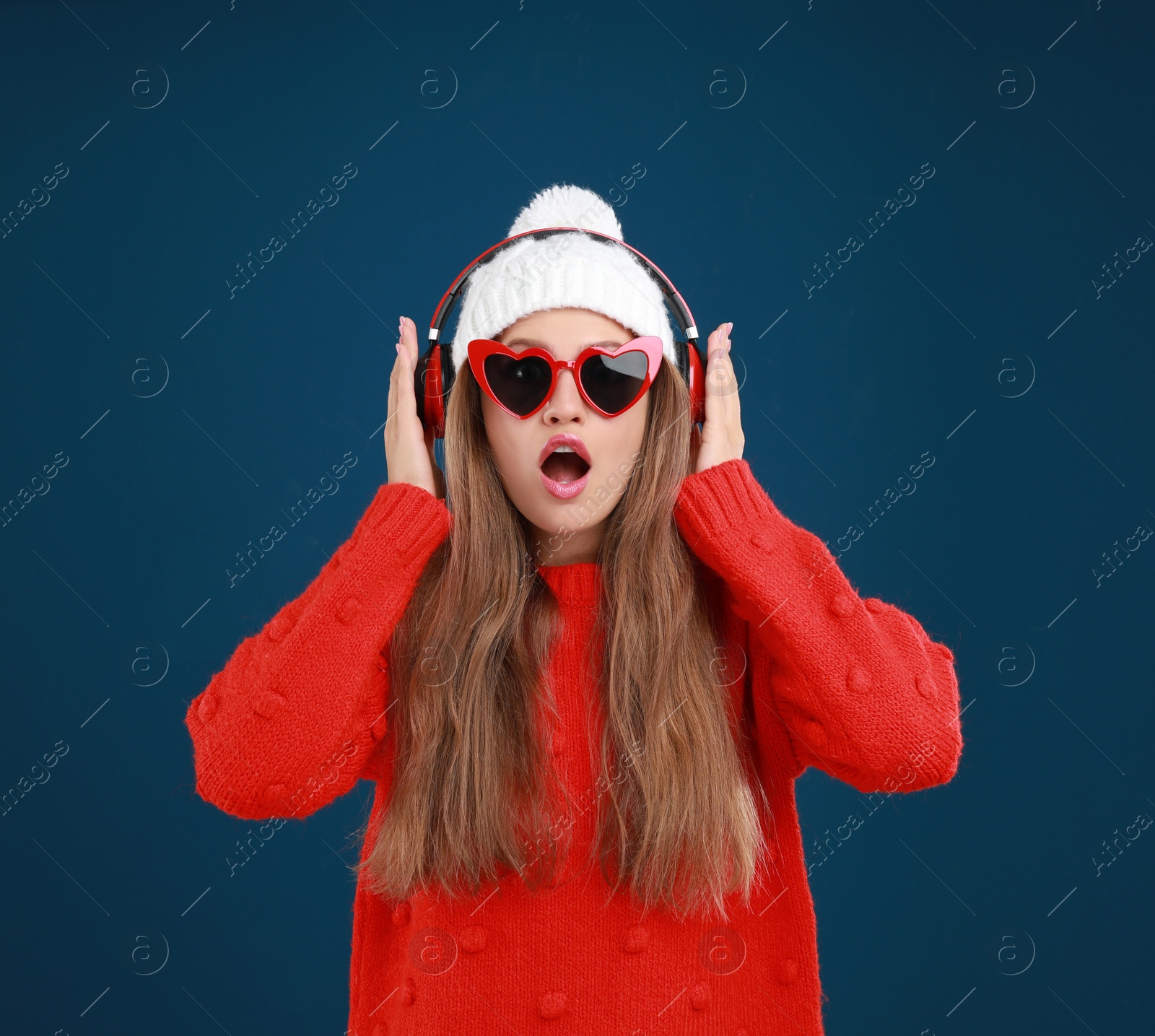 Photo of Young woman listening to music with headphones on dark blue background