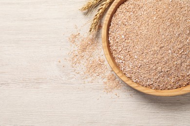 Bowl of wheat bran on white wooden table, flat lay. Space for text