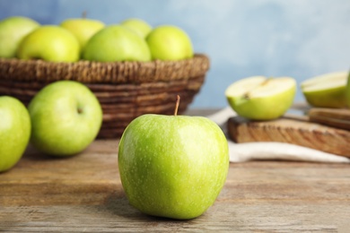 Photo of Fresh ripe green apple on wooden table against blue background, space for text