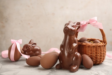 Photo of Chocolate Easter bunnies and eggs on light grey table. Space for text