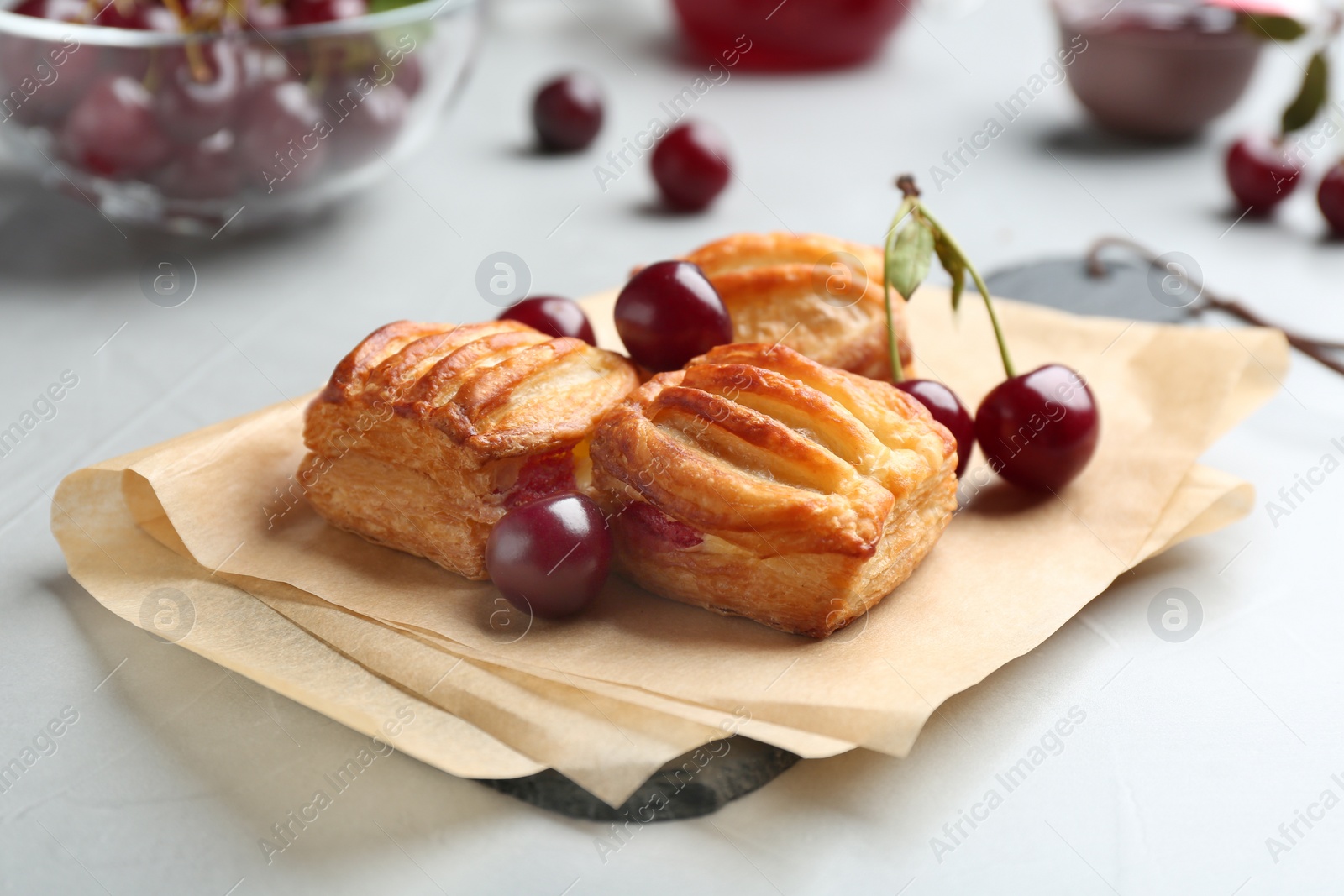 Photo of Fresh delicious puff pastry with sweet cherries served on light table