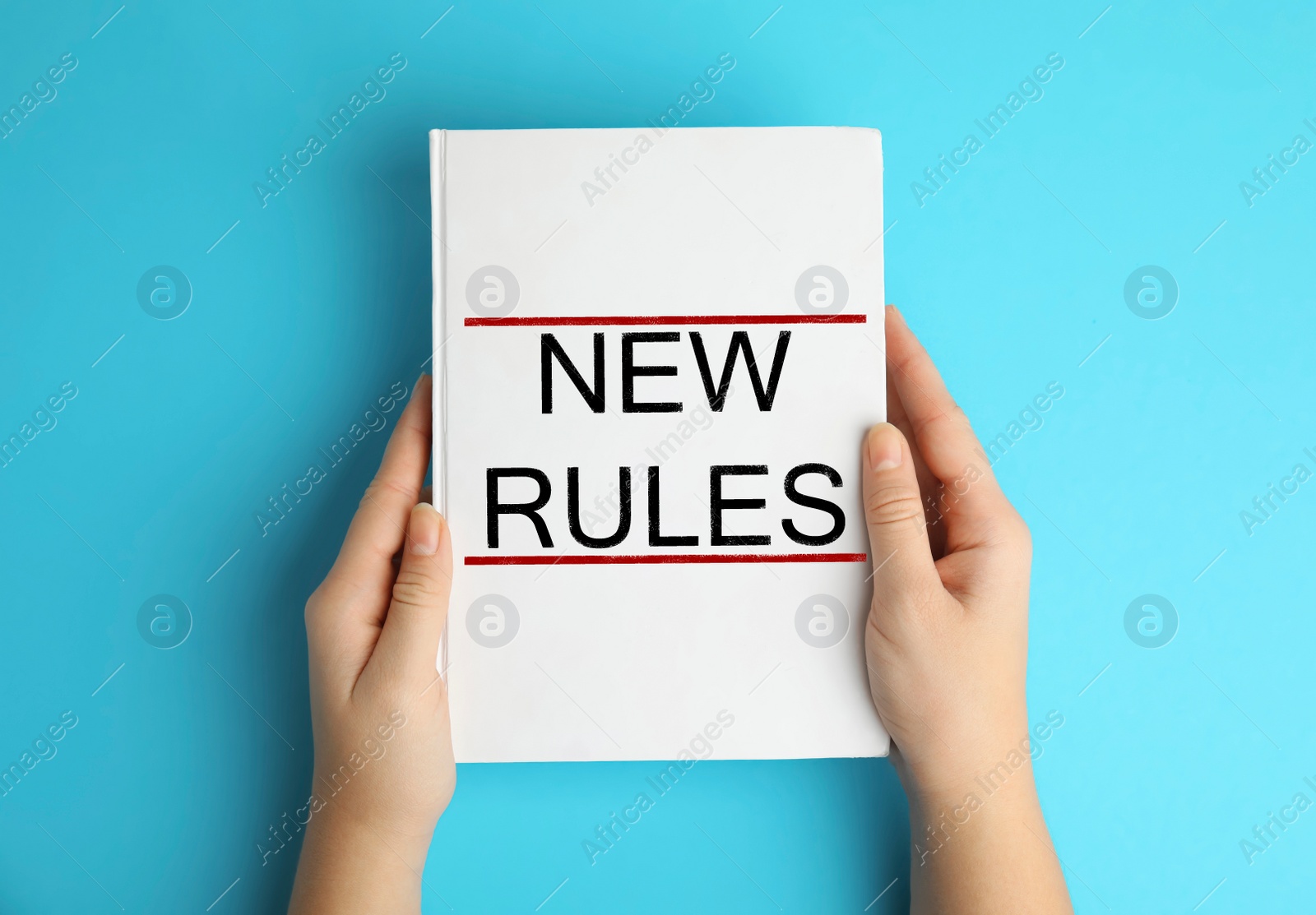 Image of Woman holding book with text NEW RULES on blue background, top view