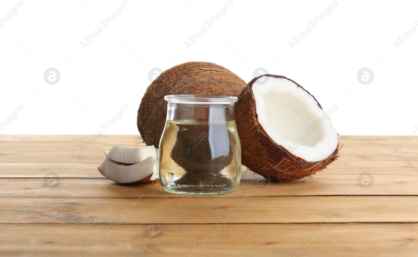 Photo of Ripe coconuts and jar with natural organic oil on wooden table against white background