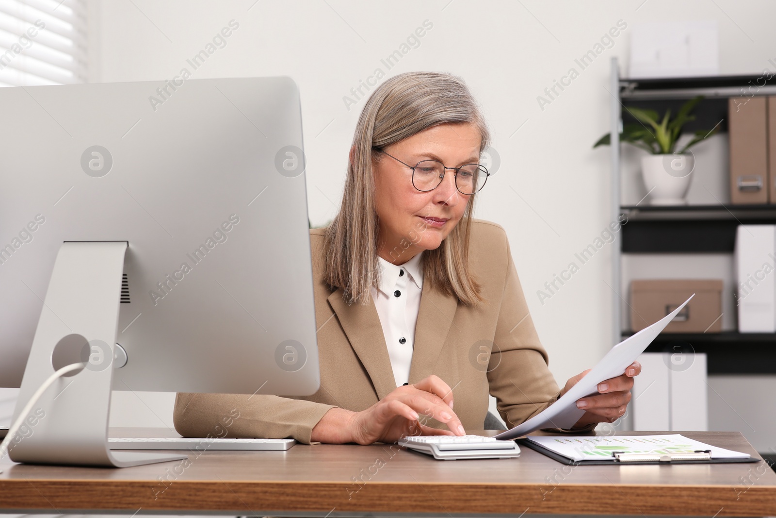 Photo of Senior accountant working at wooden desk in office