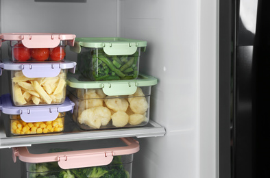 Containers with different frozen vegetables in refrigerator