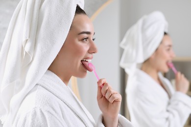 Photo of Happy woman brushing her tongue with cleaner in bathroom, space for text