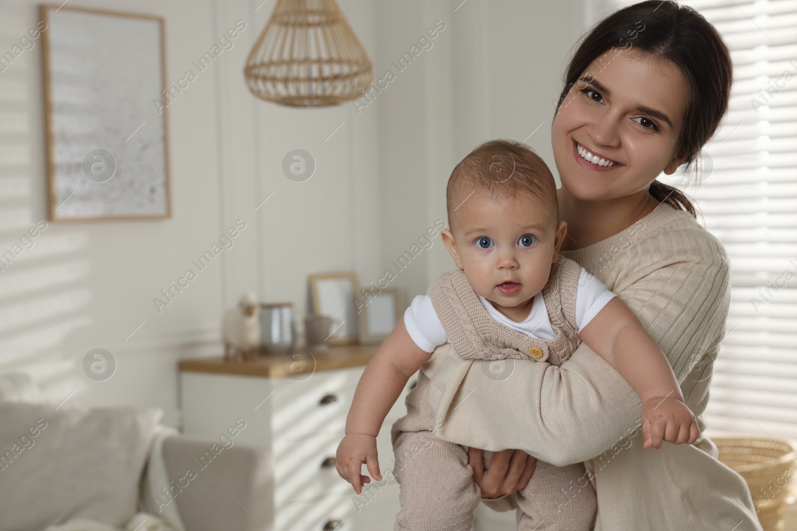 Photo of Happy young mother with her baby in living room. Space for text