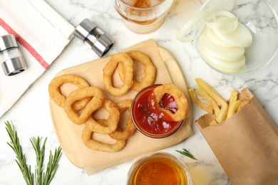 Photo of Fried onion rings served on white marble table, flat lay